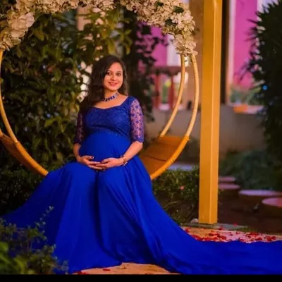 A serene moment on a floral swing. This royal blue maternity gown features delicate lace sleeves and a flowing skirt, perfect for capturing the peaceful joy of expecting.
