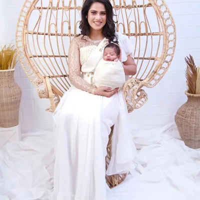This white frill saree is a unique piece for a newborn photoshoot. It comes with a designer blouse and features delicate Aari embroidery of a mother and baby on the pallu, adding a personal and sentimental touch to your photos.