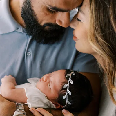 The world fades away in these moments. A new mother and father cherishing their sleeping newborn, a perfect example of an intimate, lifestyle newborn session at home.