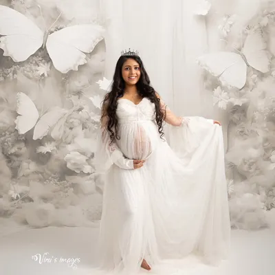 A heavenly scene surrounded by clouds and white butterflies. This portrait captures the magical transformation of motherhood, with the mother-to-be looking like a queen in her own butterfly garden.