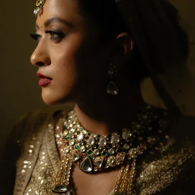 A dramatic close-up of the bride, where shadows and light play across her face, highlighting her stunning jewelry and bold makeup. A truly artistic bridal portrait.