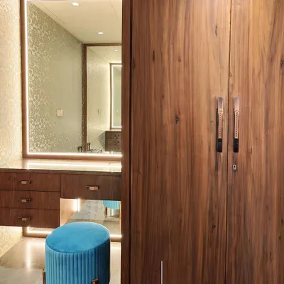 This dressing room combines the warmth of natural wood with the richness of Grigio Italian marble flooring. We focused on creating a functional yet luxurious personal space, using an illuminated mirror and a pop of color with the teal stool to add character and visual interest.