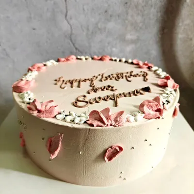 A simple and elegant cake with delicate pink floral details and a personalized message, proving that sometimes less is more.
