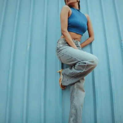 This pose adds a dynamic angle to a simple setup. The monochromatic blue palette creates a visually striking image for a modern fashion catalogue.