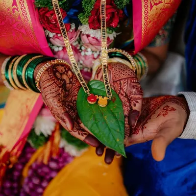A beautiful detail shot of the Mangalsutra, a sacred symbol of marriage in Maharashtrian culture, held in the couple's hands. Capturing these details is key to telling the full wedding story.