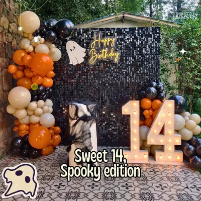 Sweet 14, spooky edition! For this Halloween-themed birthday, we designed a black sequin backdrop with a ghostly neon sign, marquee numbers, and a balloon garland in classic orange, black, and white.