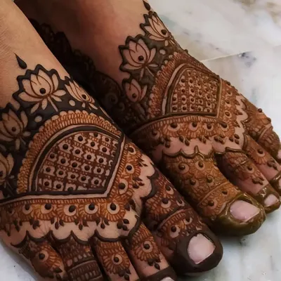 Beautiful bridal feet adorned with a lotus-themed design. The pattern features a central mandala with intricate 'jaali' work, extending to the toes for a complete and elegant look.