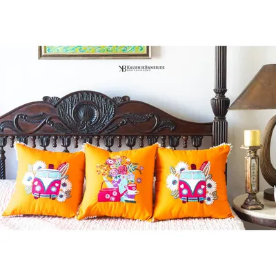 Another shot for Ekasmaye, this time featuring bright orange cushions with a fun, retro van design. The warm lighting and classic furniture create a cozy and cheerful atmosphere.