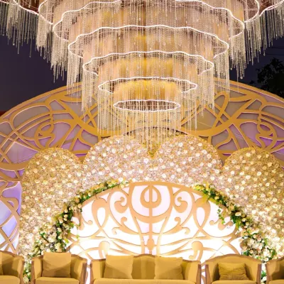 I designed this reception stage for pure opulence. A massive, cascading crystal chandelier hangs above a backdrop of white roses and intricate latticework, creating a setting of unparalleled luxury for the newlyweds.