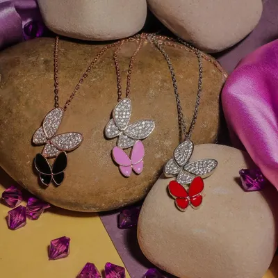 A product photoshoot featuring butterfly-themed necklaces in various colors. I used natural stones and a textured background to create an earthy, appealing aesthetic for this e-commerce jewelry collection.