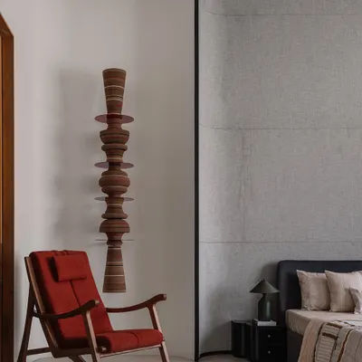 A comfortable rocking chair from Magari sits beside our custom 'Astral' wall totem, creating a quiet corner for reflection. The totem's stacked, turned-wood forms add a vertical, sculptural element that contrasts beautifully with the chair's classic lines.