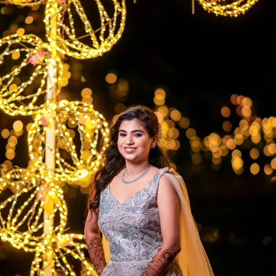 A radiant bridal portrait taken at night, with the warm glow of decorative lights creating a beautiful bokeh background.
