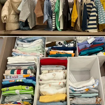 A complete view of a child's organized wardrobe. We hang jackets and shirts above, while drawers below are filled with vertically folded clothes, categorized for easy access.