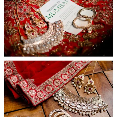 A flat lay of the bride's stunning jewelry, her red lehenga, and a 'Welcome to Mumbai' card. We love styling and capturing these detail shots that set the scene for your wedding story.