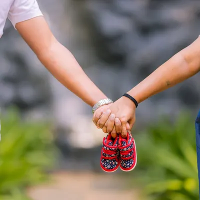 A beautiful close-up shot focusing on the couple holding tiny baby shoes, a classic and heartwarming maternity announcement photo.