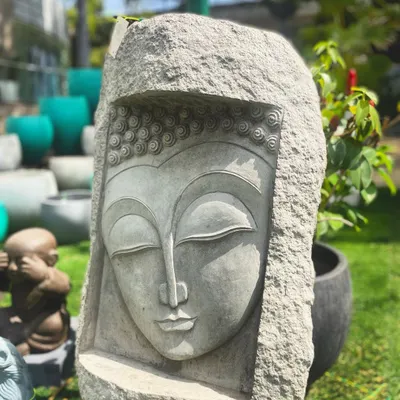 This serene Buddha face mural, carved into a solid block of stone, is a powerful symbol of enlightenment. The closed eyes and gentle smile represent a peaceful state of mind, perfect for a meditation garden or tranquil room.
