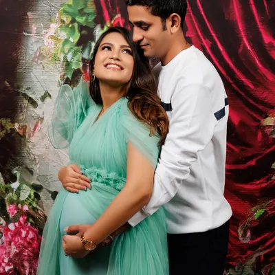 The connection between expecting parents is so beautiful to witness. This studio maternity portrait, with a soft green gown and a rich floral backdrop, captures that shared excitement and love.