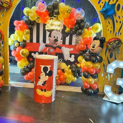 Yeh ek classic Mickey Mouse theme birthday decoration hai. Isme maine red, black, aur yellow balloons, character cutouts, aur light-up marquee number '3' ka istemaal kiya hai.