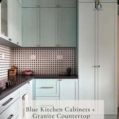 This light blue kitchen showcases a beautiful material pairing of shaker-style cabinets with a classic granite countertop. The black and white patterned backsplash adds a graphic element, creating a timeless yet modern look.