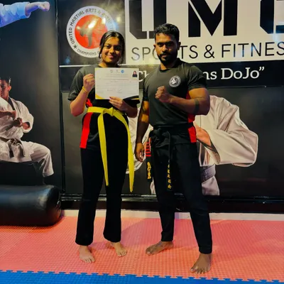 A student proudly holding her certificate after successfully passing the Kickboxing Belt Grading Exam and earning her Yellow Belt.