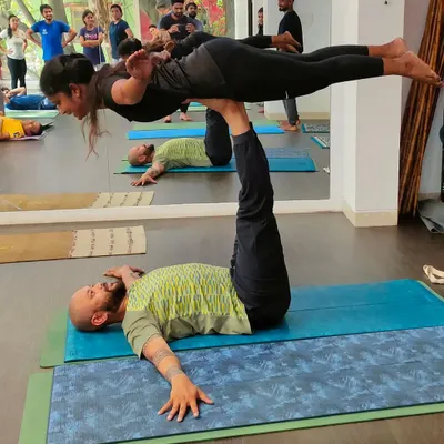 An instructor bases a student in a therapeutic Acro Yoga pose. This "bird" pose helps to lengthen the flyer's spine and is built on a foundation of trust and stability.