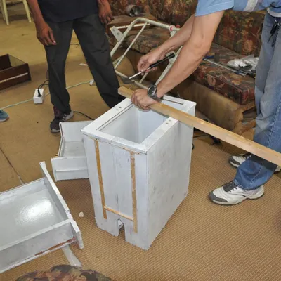 A participant works on repairing a small wooden cabinet. Our workshops provide the space and tools for you to tackle small furniture and woodwork projects.