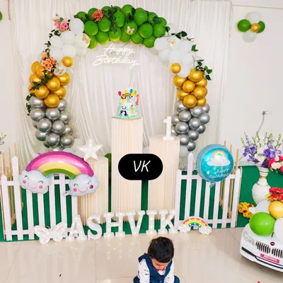 A full view of my decoration work for a first birthday. This setup includes a circular balloon arch in green, gold, and silver, custom name lettering, and themed props like the rainbow foil balloon to create a complete look.