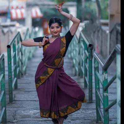 A graceful pose captured during a photoshoot at a temple. The setting provides a serene and powerful backdrop that complements the traditional aesthetics of Bharatanatyam.