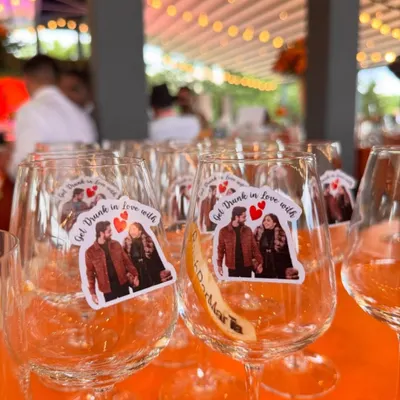 Personalization makes an event truly yours. For this Hermès-themed sundowner, we adorned the wine glasses with custom stickers featuring the couple's photo and the fun phrase 'Get Drunk in Love with', adding a charming and personal touch.