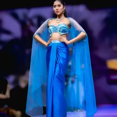 A stunning shot from Bangalore Fashion Week. The model's powerful pose and the flowing blue cape create a dramatic and memorable runway moment.