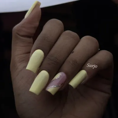 A simple yet sunny look. This manicure features long, square shaped nails in a matte pastel yellow, with a single accent nail featuring a diagonal silver glitter stripe.