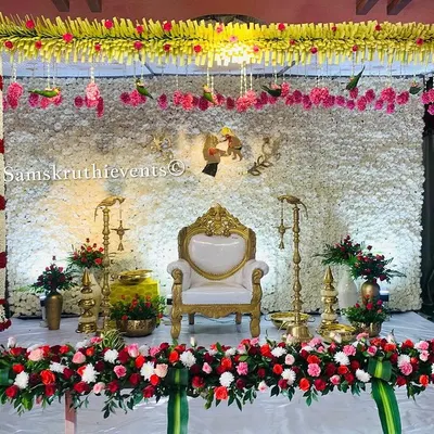 An elegant and unique stage for a traditional ceremony. The backdrop is a dense wall of white jasmine, framed by columns of flowers and a border of red and white roses.