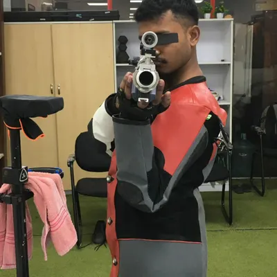 A 10m Air Pistol shooter demonstrates the one handed stance and focus required for this discipline. The shooting jacket provides stability to the upper body, which is crucial for accuracy.