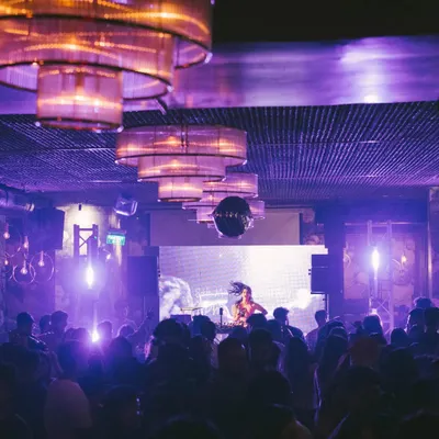 A view from my console during a packed club night. The combination of purple lights, a disco ball, and a full house is my ideal work environment.