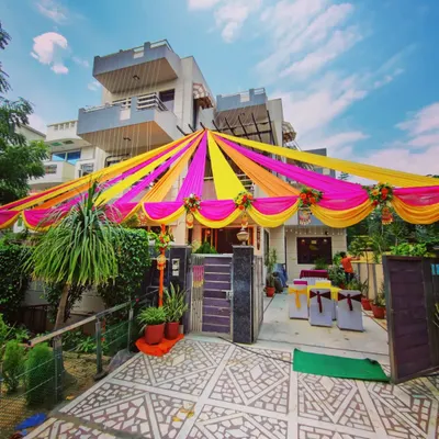 For home-based functions like a Mehandi or Sangeet, I transform the entire front of the house. Here you can see a full canopy of bright pink and yellow fabric drapes, creating a festive atmosphere right from the street.