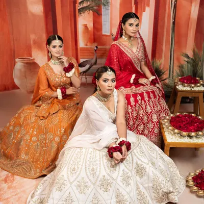 I believe in offering a spectrum of choices for the modern bride and her party. This trio of lehengas in festive red, serene white, and vibrant orange showcases the variety of moods and styles we can explore for your wedding celebrations, from the main event to the sangeet.