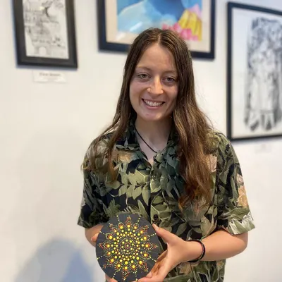 A participant proudly displays her beautiful dot mandala artwork. This therapeutic art form involves creating intricate patterns with dots, resulting in a stunning, meditative piece.
