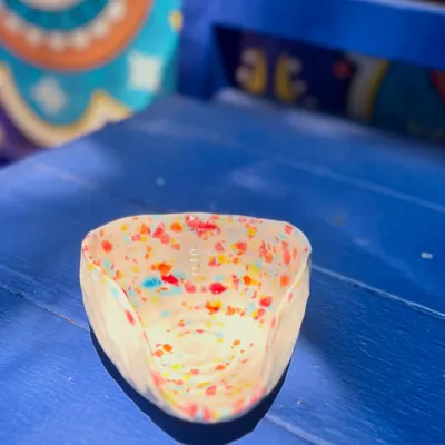 A small, hand-pinched bowl from the Kaleidoscope Collection, alive with a confetti of colors. These little trinket dishes are perfect for holding rings, spices, or just for adding a pop of color to a shelf.
