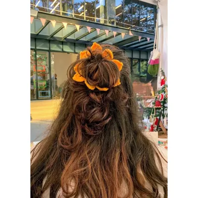 Our handmade sunflower scrunchie is a bestseller for a reason. It’s a fun and bright way to tie up your hair, shown here styled in a simple bun.