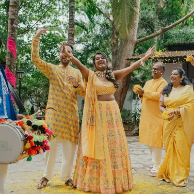 A bride's joyful entrance during her Haldi ceremony, surrounded by family and the beat of the dhol.