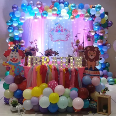 Step right up to a carnival-themed birthday party. This vibrant setup for Irfan features a colorful balloon arch, fun character cutouts like a clown and lion, and illuminated marquee letters for the name.