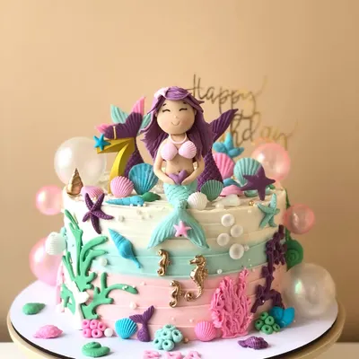 An underwater dream, this mermaid cake is decorated with pastel buttercream waves, edible shells, starfish, and a beautiful mermaid topper.