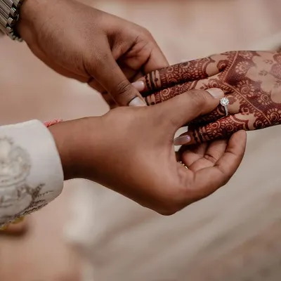 A close-up of the ring exchange, a symbol of commitment. We focus on capturing these crucial details, including the intricate henna designs that tell their own story.
