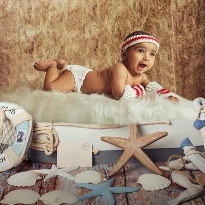 This little sailor is ready for an adventure. A 6-month sitter session is the perfect time to use fun themes like this nautical setup, complete with a lifebuoy, starfish, and an anchor. His excited expression shows off his budding personality.