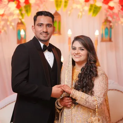 An elegant portrait of the couple at their wedding reception. The groom in his classic tuxedo and the bride in her shimmering gown look ready to celebrate their new beginning.