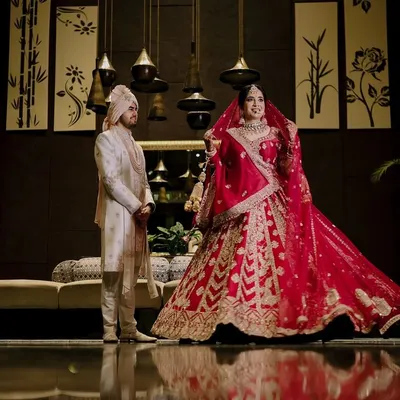 A stunning full-length portrait of Ritish and Aastha on their wedding day in Delhi, capturing the grandeur of their attire and the elegance of the moment.