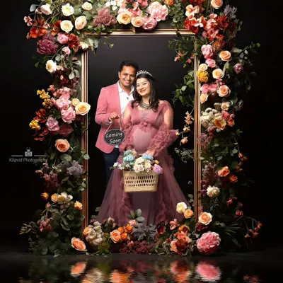 A living portrait, framed in flowers. This elaborate floral setup creates a breathtaking, artistic announcement. The reflection adds a layer of depth, making it a truly magical and memorable image.