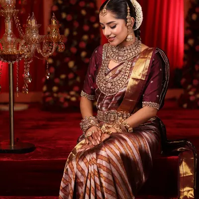 A demure pose from a South Indian bride, showing the rich texture of her Kanjeevaram saree and layered necklaces.