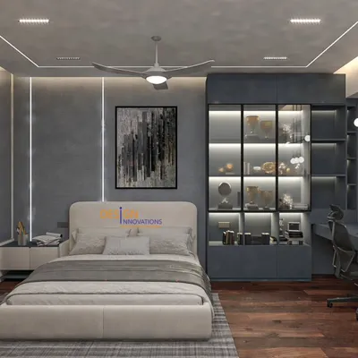 This view of the modern grey bedroom highlights the fully integrated workspace. We designed a long desk with sleek overhead lighting, ensuring the work corner is functional without disrupting the room's serene aesthetic. The glass-front cabinet provides stylish storage.