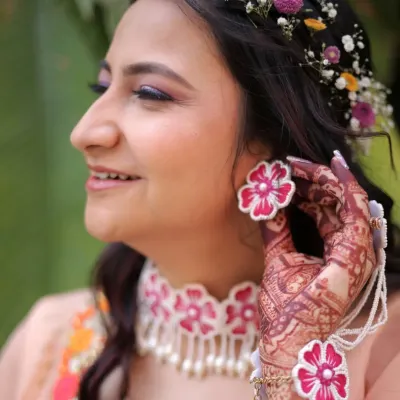 A close-up on the details of a fun Haldi look. The floral jewelry, including the earrings and choker, is the centerpiece, complemented by a pop of purple on the eyes and fresh, glowing skin.